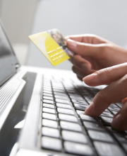 Photo of hands holding card over laptop keyboard