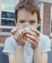 School child holding fidget spinner in front of face, looking through it at the camera